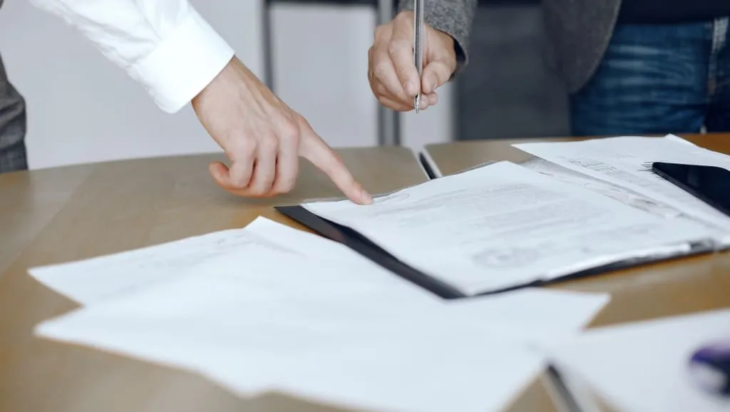 Mãos apontando para um documento sobre a mesa